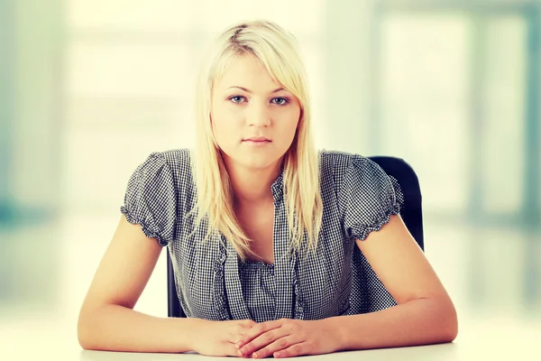 Young woman sitting with hands on desk — Stock Photo, Image