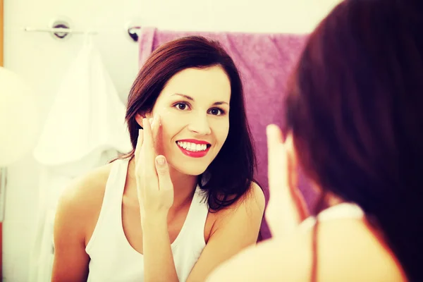 Young woman applying creme at  her face. — Stock Photo, Image