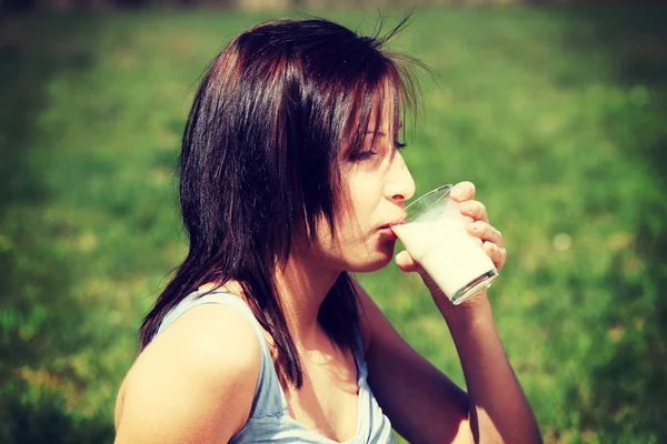 Girl on meadow is drinking glass of milk. — Stock Photo, Image
