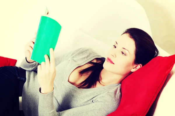 Bella donna che legge un libro su un divano . — Foto Stock