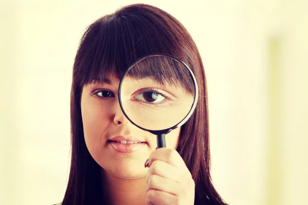 Businesswoman looking into a magniying glass Royalty Free Stock Photos