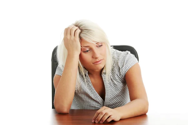 Mujer joven estresada sentada detrás de un escritorio — Foto de Stock
