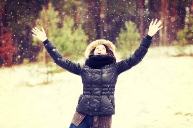 Happy girl with hands up when its snowing. clipart