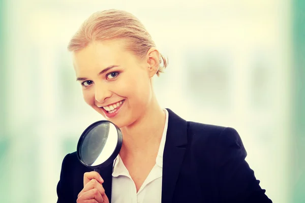 Business woman looking into a magnifying glass — Stock Photo, Image