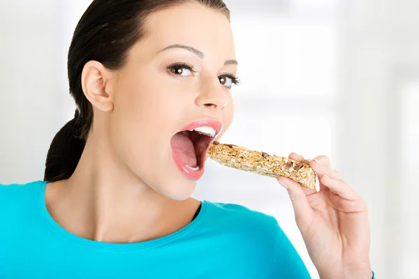 Mulher comendo barra de doces de cereais — Fotografia de Stock
