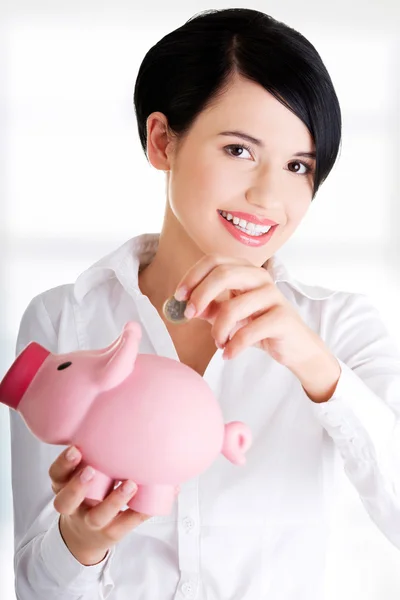 Zakenvrouw een munt ingebruikneming een piggy bank — Stockfoto