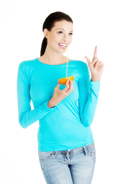 Beautiful young woman drinking juice from orange. — Stock Photo, Image