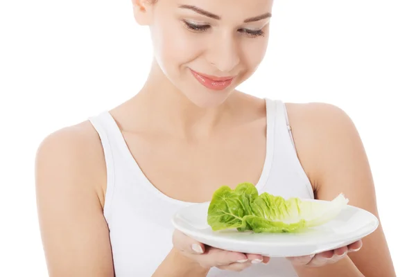 Young slim woman with lettuce on a plate. — Stock Photo, Image
