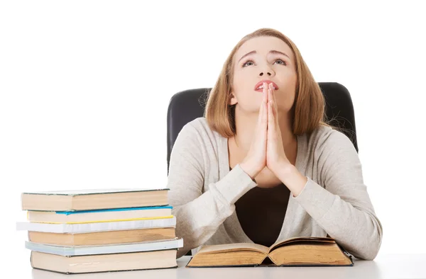 Beautiful student woman sitting and praying with stack of books. — Stock Photo, Image