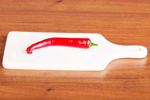 Fresh chili pepper lying on kitchen board. — Stock Photo, Image