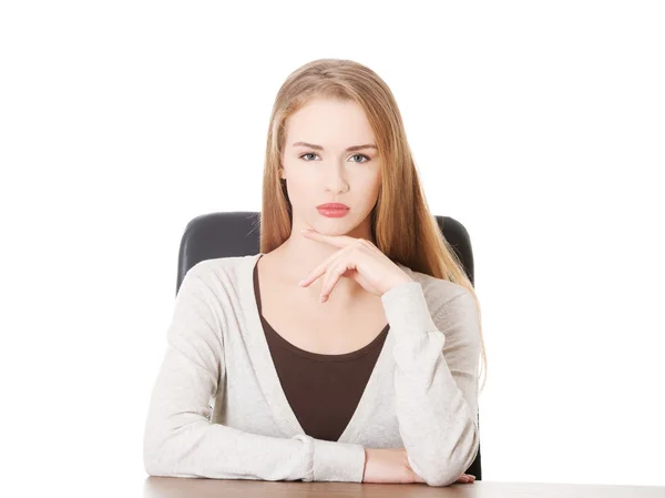 Hermosa mujer casual sentada junto a un escritorio . — Foto de Stock