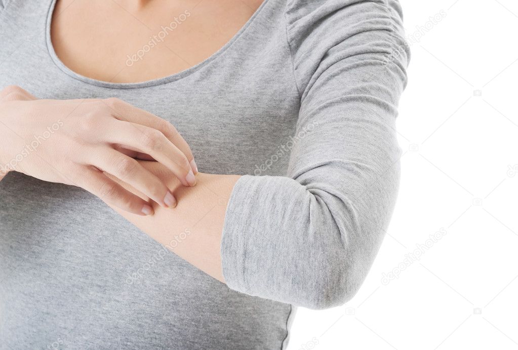 Young woman is scratching herself on arm.