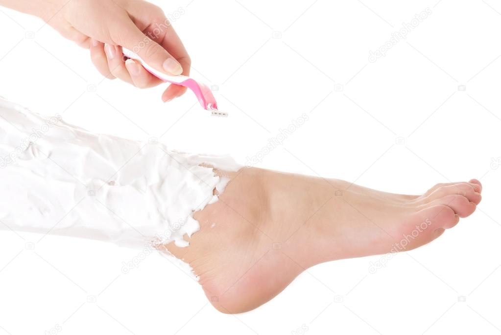 Beautiful woman is shaving her legs with razor and foam.