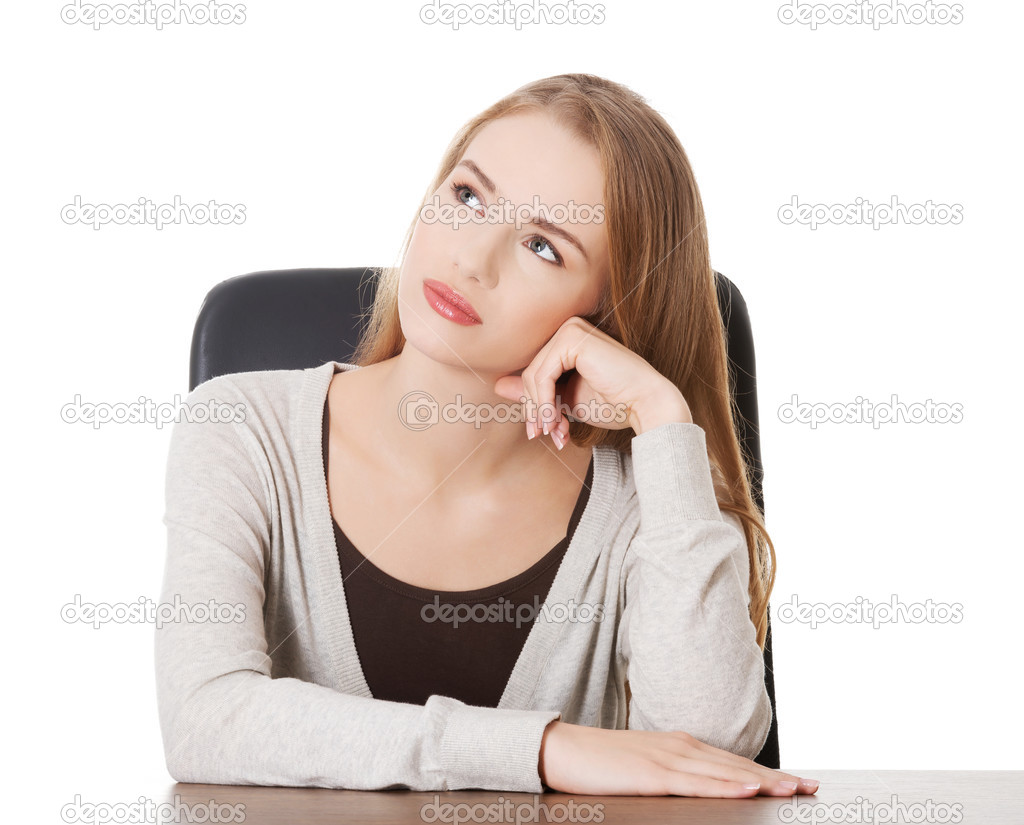 Woman sitting by a desk and day- dreaming.