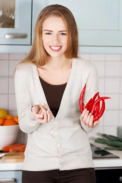 Vrouw houdt chili peppers en knoflook. — Stockfoto