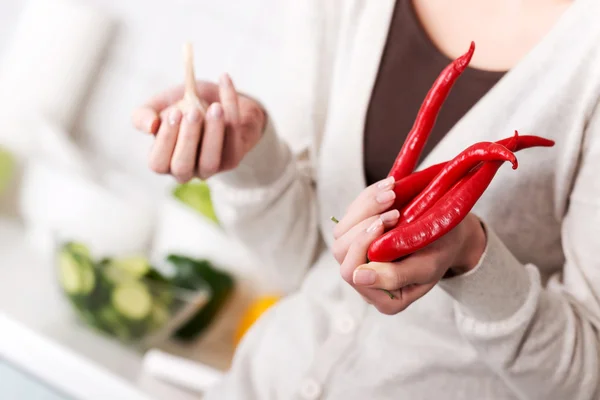 Woman is holding chili peppers and garlic. — Stock Photo, Image