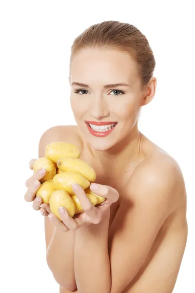 Naked woman holding raw potatoes in hands. — Stock Photo, Image