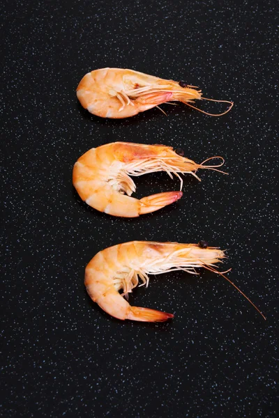 Drie gescheiden garnalen liggend op een keukentafel. — Stockfoto