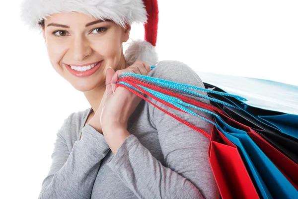 Vrouw in Kerstman hoed met shopping tassen. — Stockfoto