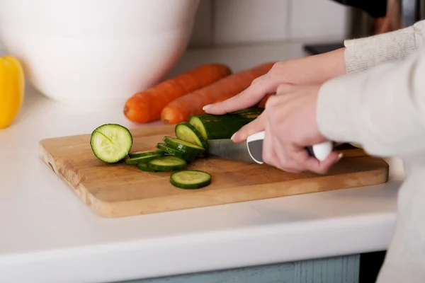 Mulher no corte de pepino na placa da cozinha . — Fotografia de Stock