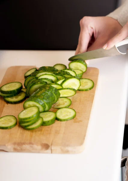 Woman in cutting cucumber on kitchen board. — Stock Photo, Image