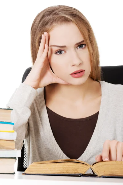 Studerande kvinna sitter vid trave böcker — Stockfoto