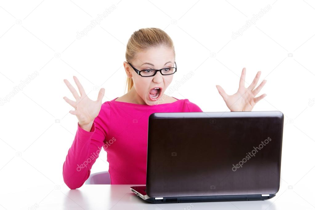 Young surprised woman sitting in front of laptop.