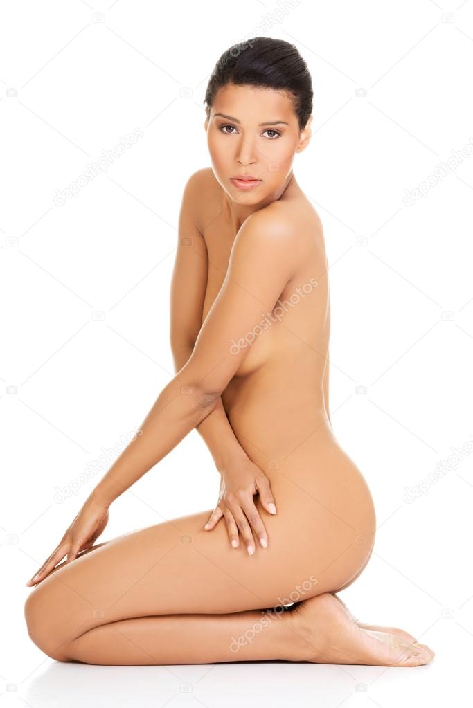 Attractive naked woman sitting on knees. Side view.