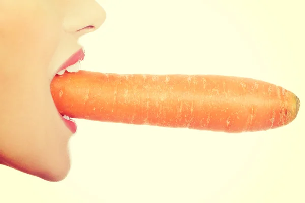 Profile of woman eating raw carrot. Royalty Free Stock Photos