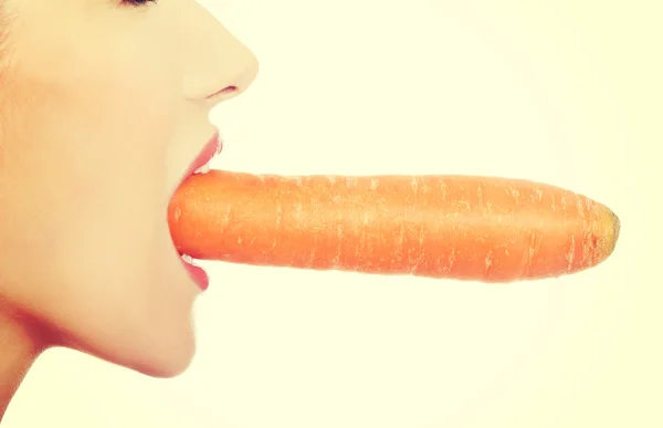 Profile of woman eating raw carrot. Stock Picture