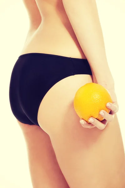 Nalgas femeninas con naranja . — Foto de Stock