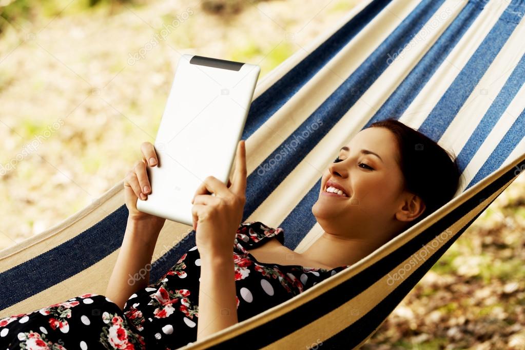 Woman Relaxing In Hammock With  E-Book