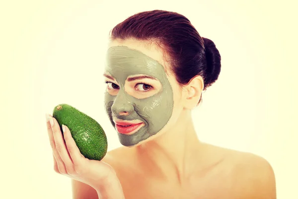 Beautiful woman with facial mask holding avocado — Stock Photo, Image