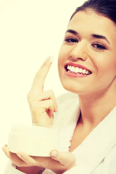 Beautiful woman in bathrobe with face cream — Stock Photo, Image