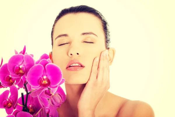 Mulher nova com pele de saúde e orquídea — Fotografia de Stock