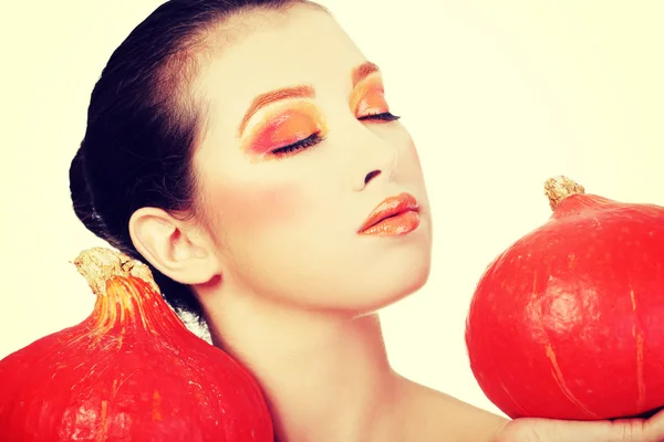 オレンジを持つ女性がカボチャを保持しているをメイクアップします。 — ストック写真