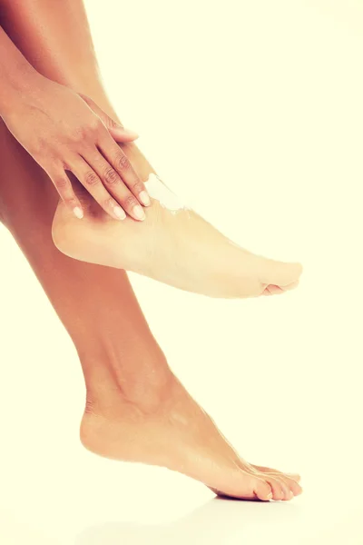 Mani femminili che trattano piedi con crema idratante — Foto Stock