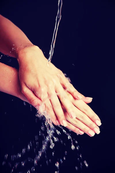Agua cayendo sobre las manos femeninas — Foto de Stock