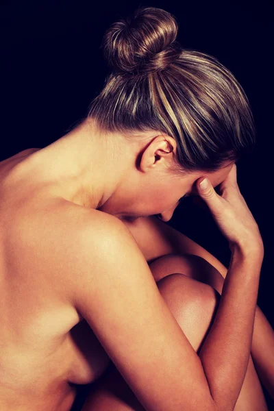 Naked woman sitting and touching her forehead. — Stock Photo, Image