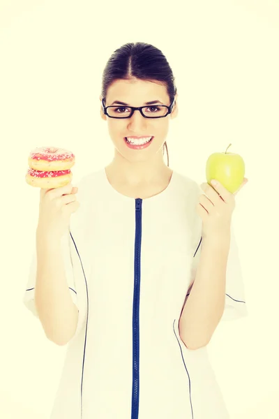 Arzt hält Apfel und Donuts in der Hand. — Stockfoto