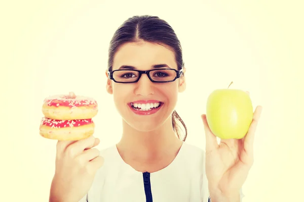 Doctor holding an apple and doughtnuts. — Stock Photo, Image