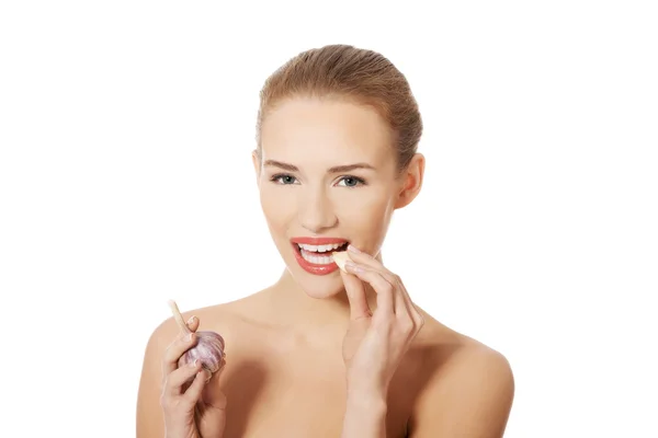 Beautiful woman with raw garlic in mouth. — Stock Photo, Image