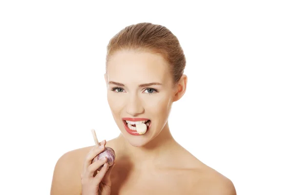 Vacker kvinna med rå vitlök i mun. — Stockfoto