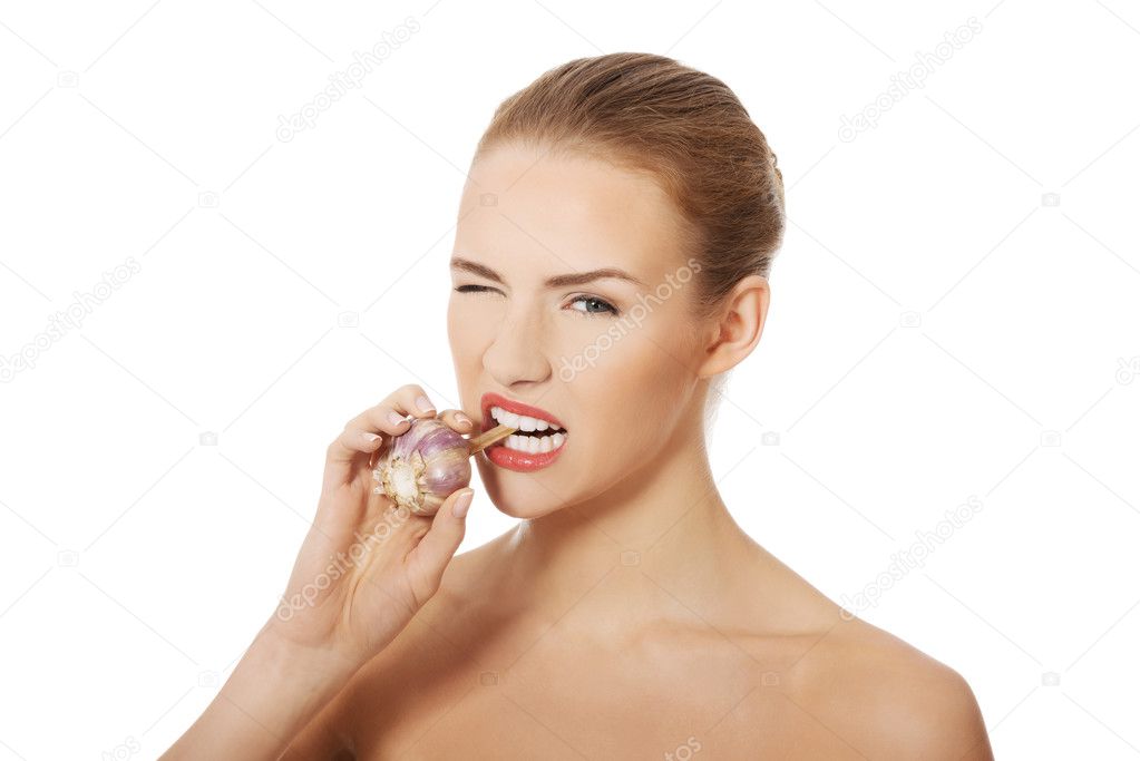 Beautiful woman with raw garlic in mouth.