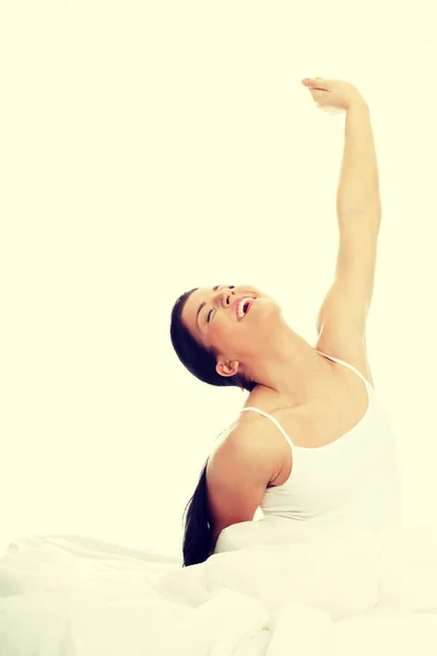 Happy young woman stretching in bed — Stock Photo, Image