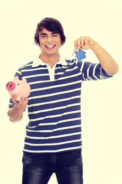 Junger Mann mit Schlüssel und Sparschwein. — Stockfoto