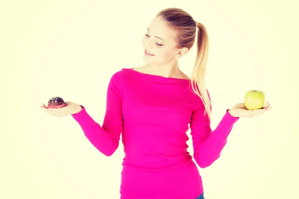 Mujer sosteniendo una manzana y una galleta . —  Fotos de Stock