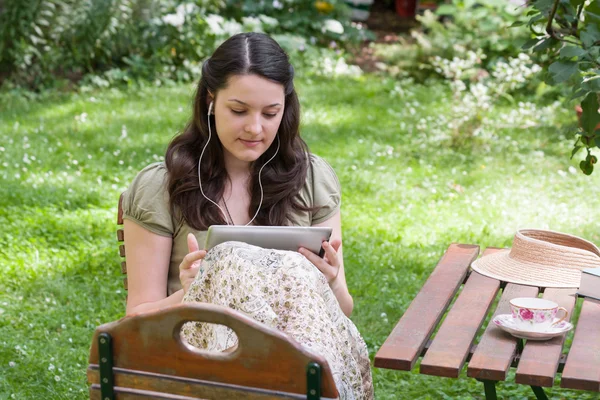 Ung kvinna med TabletPC i en trädgård — Stockfoto