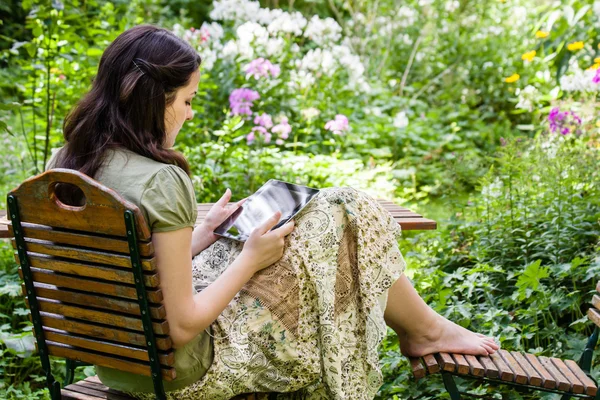 Mujer joven con tablet PC en un jardín — Foto de Stock