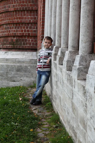 Băiatul stă lângă peretele de cărămidă — Fotografie, imagine de stoc